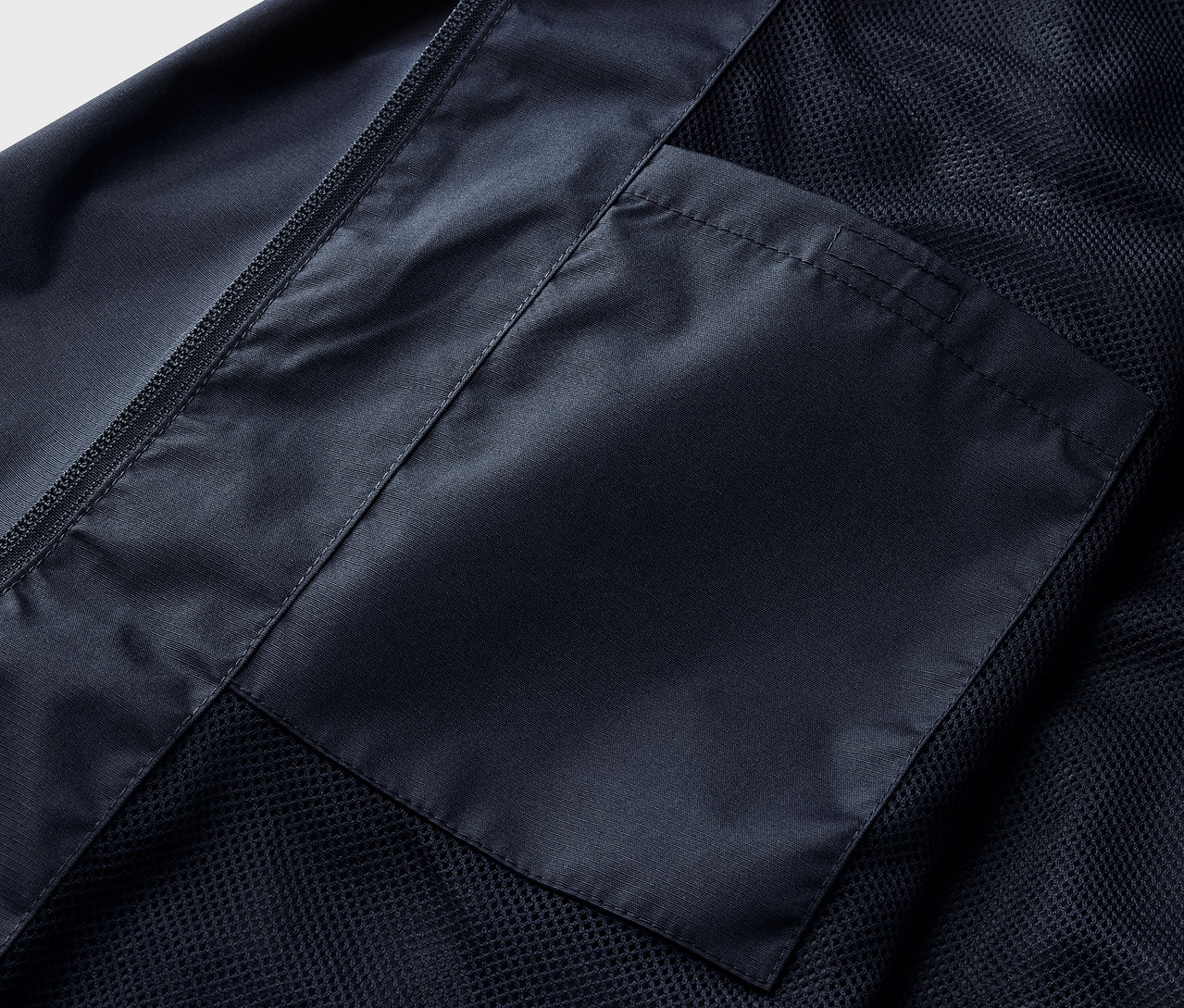 Detail námornícky modrej bundy do dažďa s vreckom.