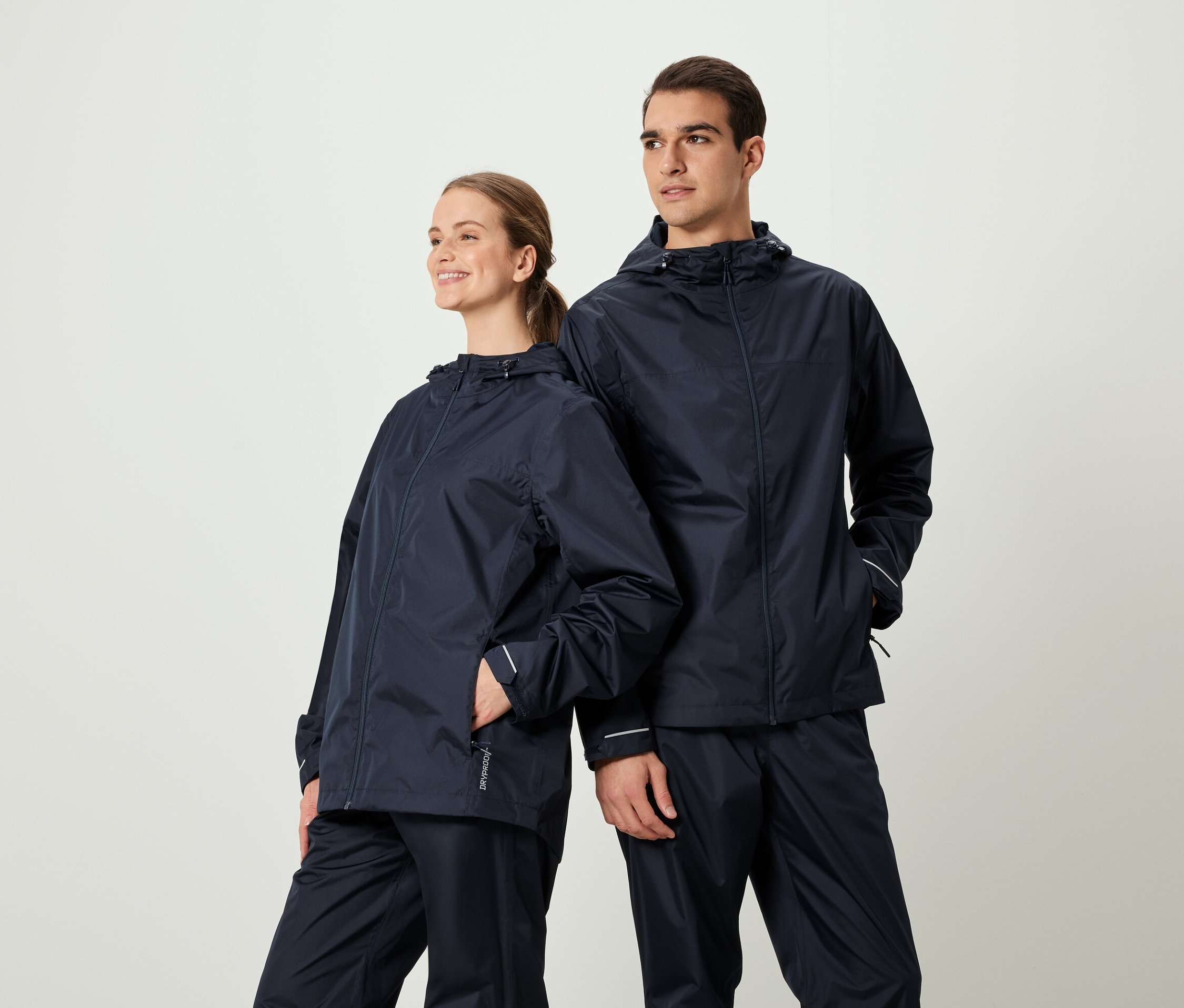 Dvaja ľudia pózujú v zodpovedajúcich tmavomodrých bundách a nohaviciach do dažďa.