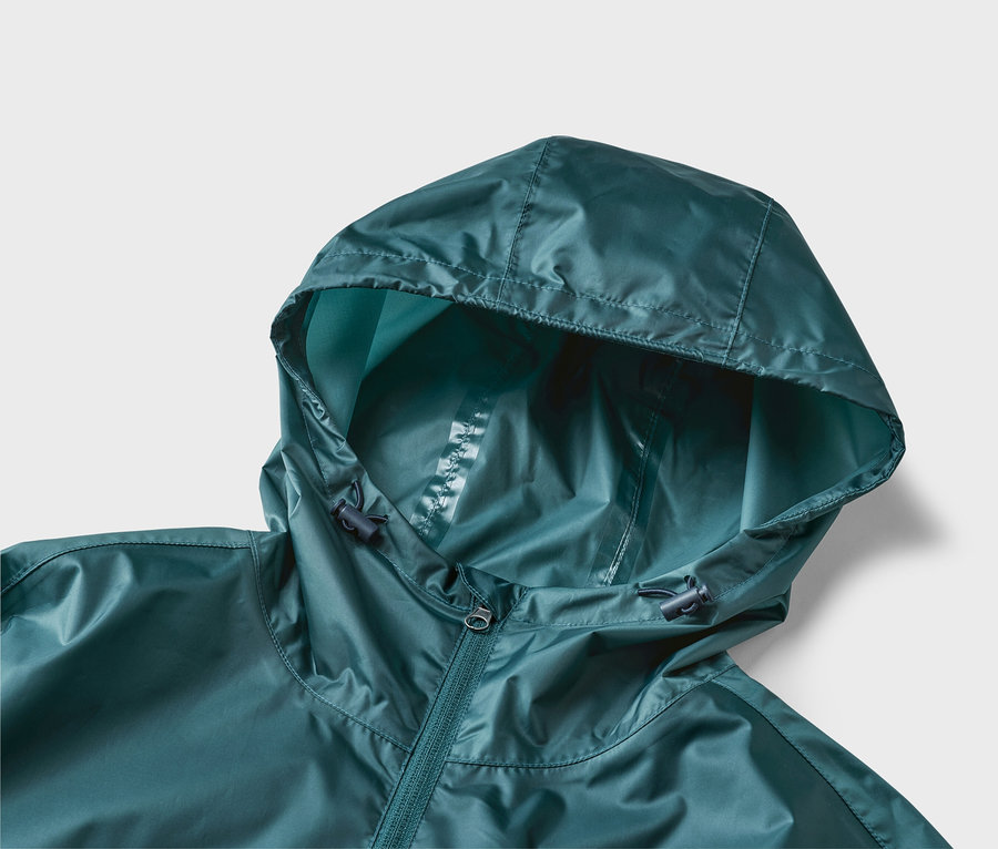 Detailný záber tmavozelenej bundy do dažďa s kapucňou a zipsom na neutrálnom pozadí.