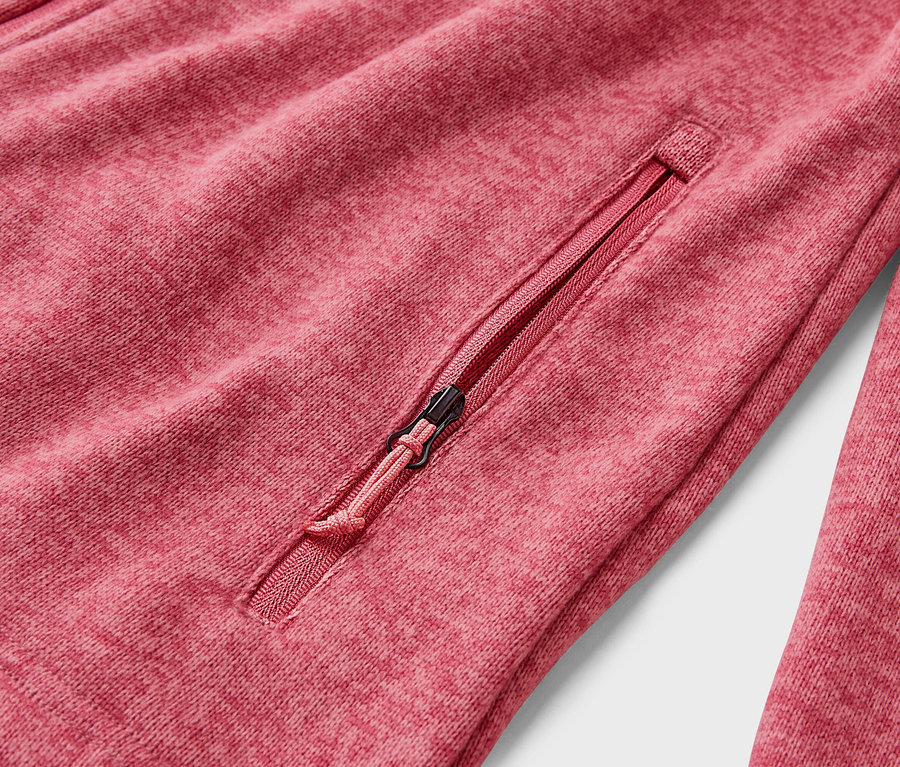 Detail červenej fleecovej bundy s vreckom na zips.