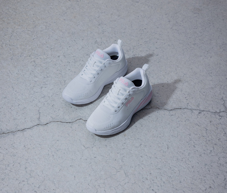 Dve biele tenisky Fila s ružovým logom ležia na sivom pozadí.