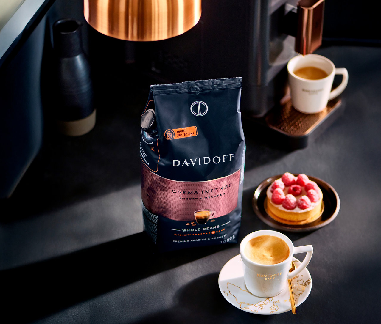 Stôl s šálkou kávy, koláčom a balením DAVIDOFF CAFÉ Crema Intense.