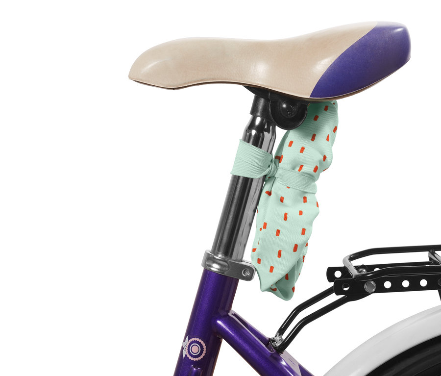 Detský poťah na sedadlo bicykla s červenými bodkami pripevnený k sedadlu bicykla.