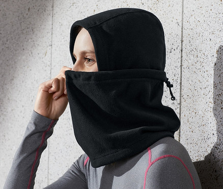 Žena si upravuje čiernu kuklu z mikroflísu na hlave.