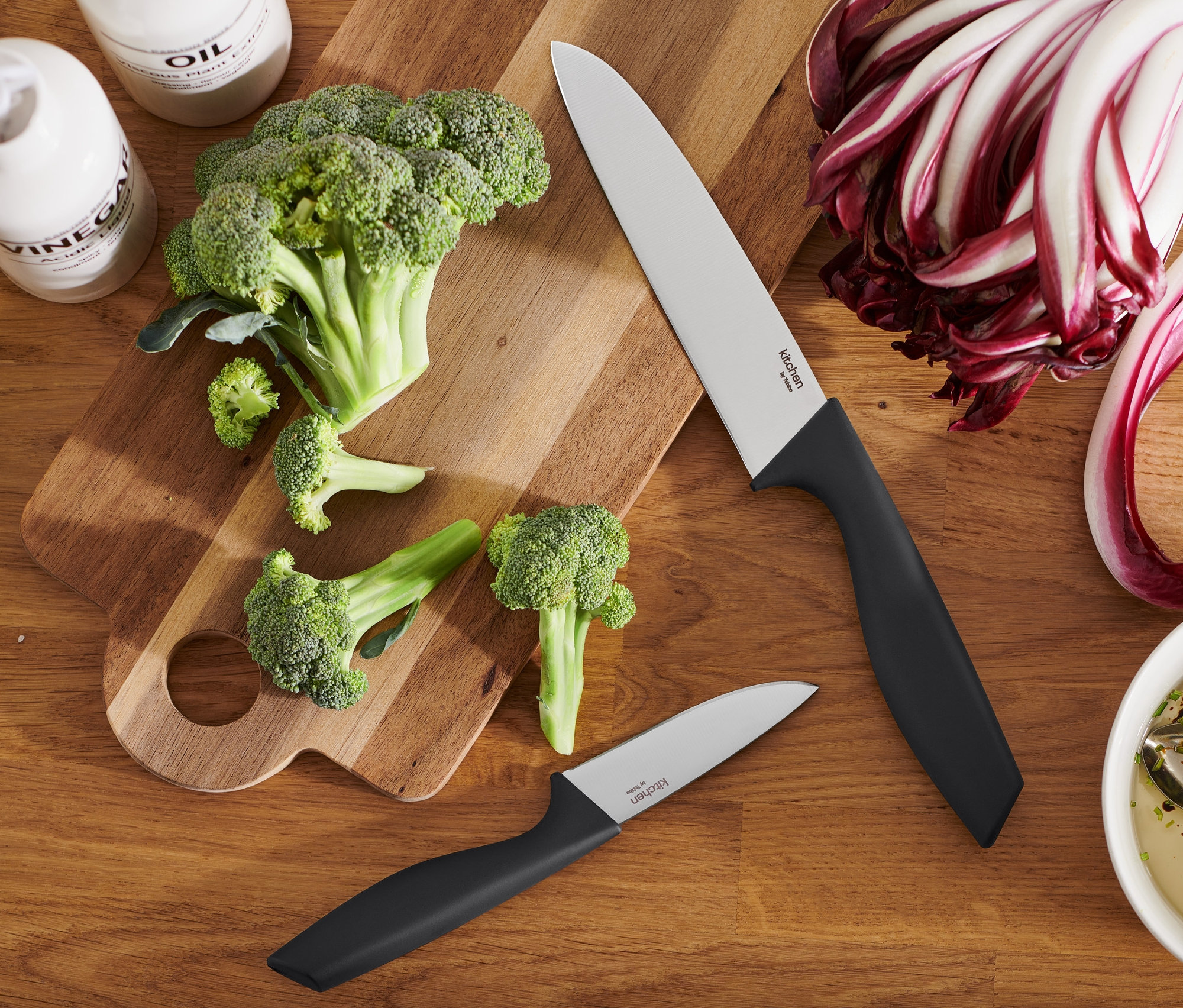 Brokolica a nože na drevenej doske na krájanie. Súprava kuchynských nožov je k dispozícii.