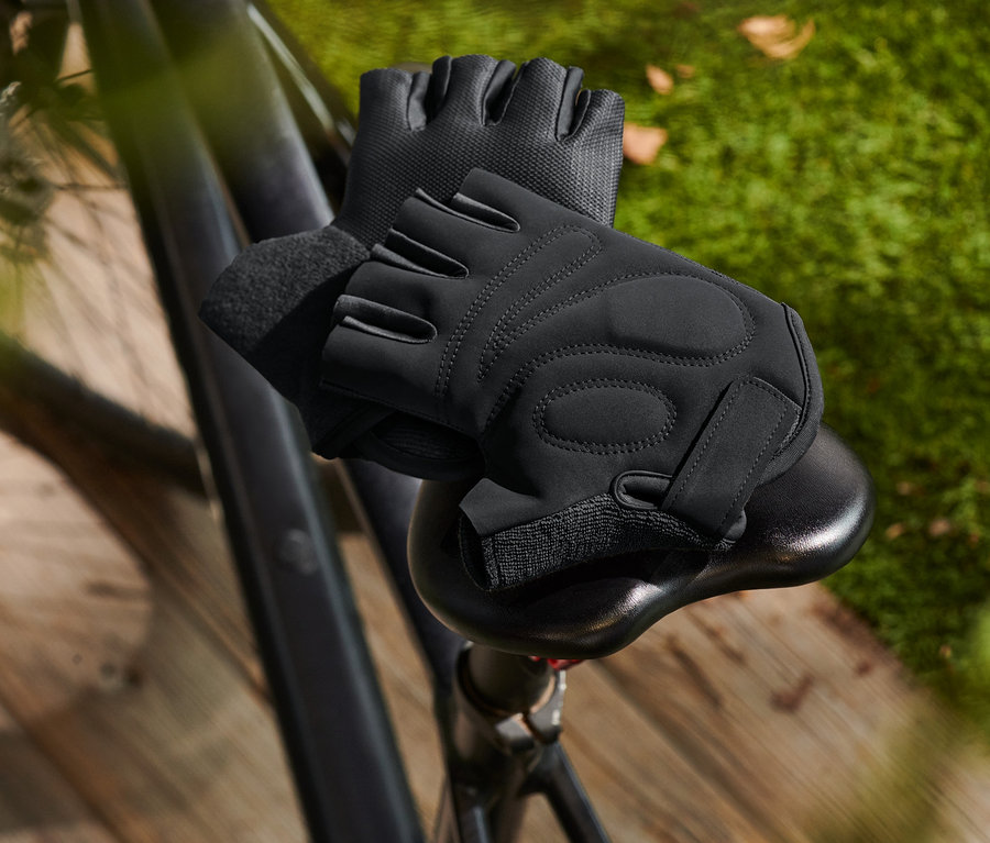Čierne cyklistické rukavice ležia na sedle bicykla.