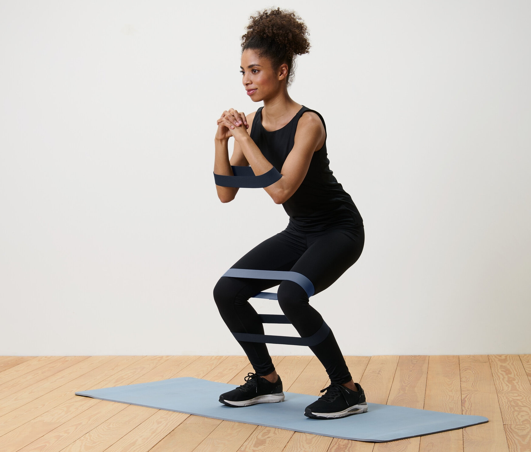 Žena cvičí drepy s posilňovacími pásmi, 3 ks, na podložke.