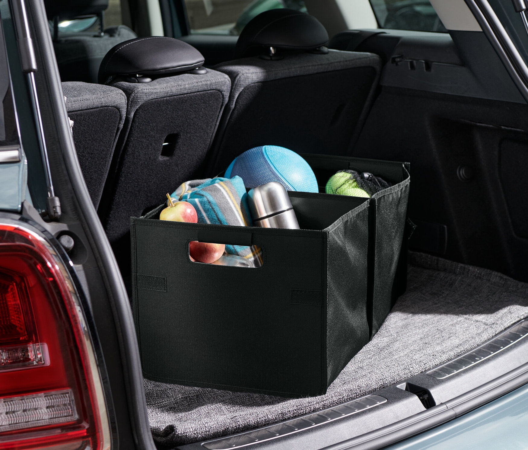 Skladací box do auta v kufri auta, vnútri boxu je ovocie, deka, termoska a lopty.
