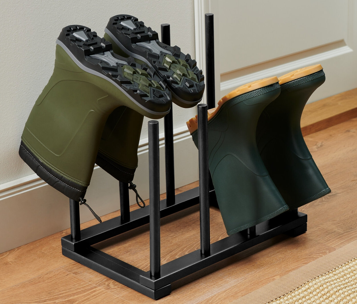 Dva páry zelených gumákov v držiaku na topánky.