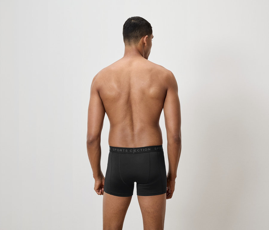 Muž chrbtom k fotoaparátu má na sebe čierne boxerky.