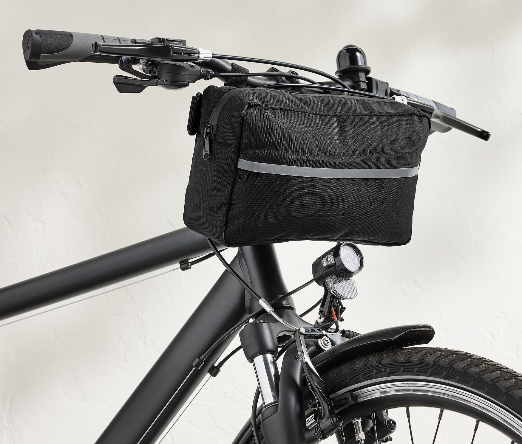 Čierna taška na riadidlá bicykla 2 v 1 na riadidlách čierneho bicykla.