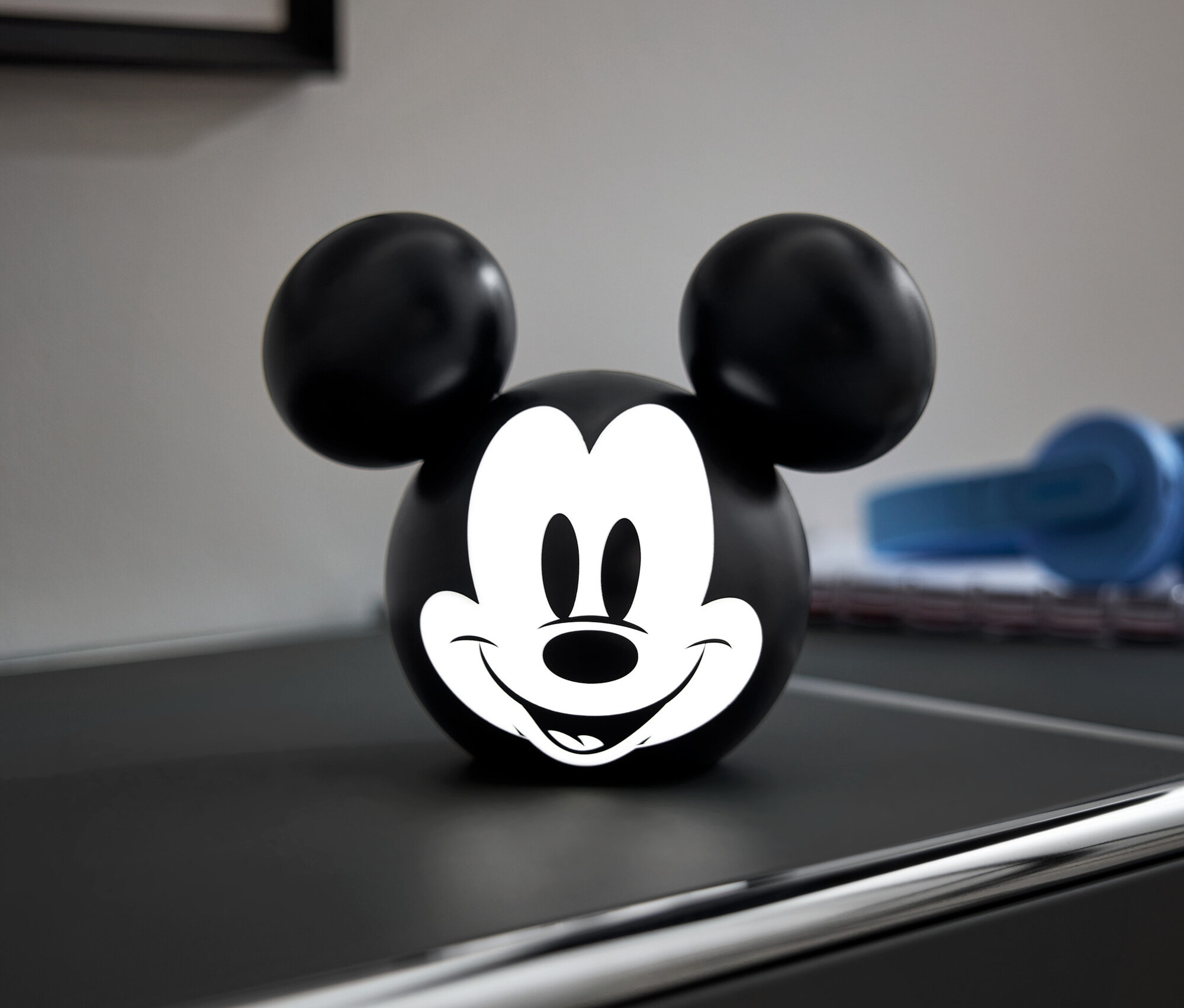 Čierna guľa s bielou tvárou Mickey Mousa na čiernej komode.
