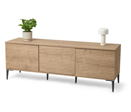 Svetlý drevený sideboard s rastlinou v kvetináči a lampou.