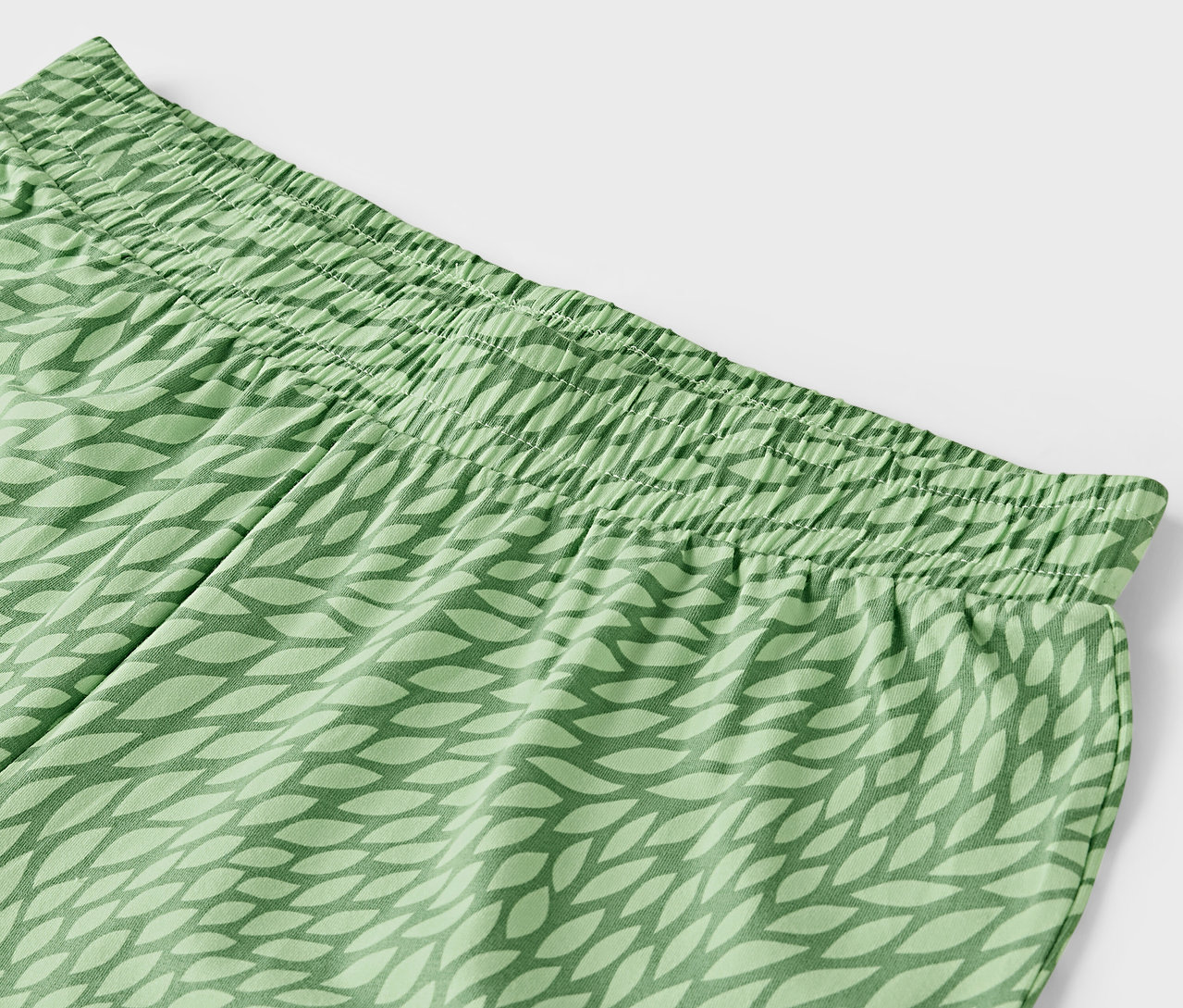 Detail zelených nohavíc s elastickým pásom a vzorom listov.