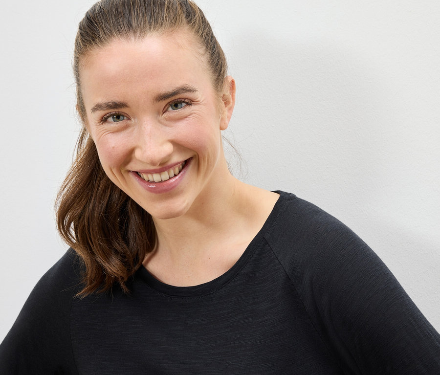 Portrét usmievajúcej sa ženy s hnedými vlasmi v čiernom tričku.