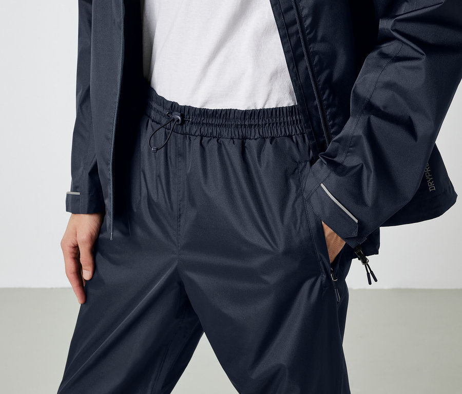 Osoba má na sebe tmavomodré nepremokavé nohavice a bundu.