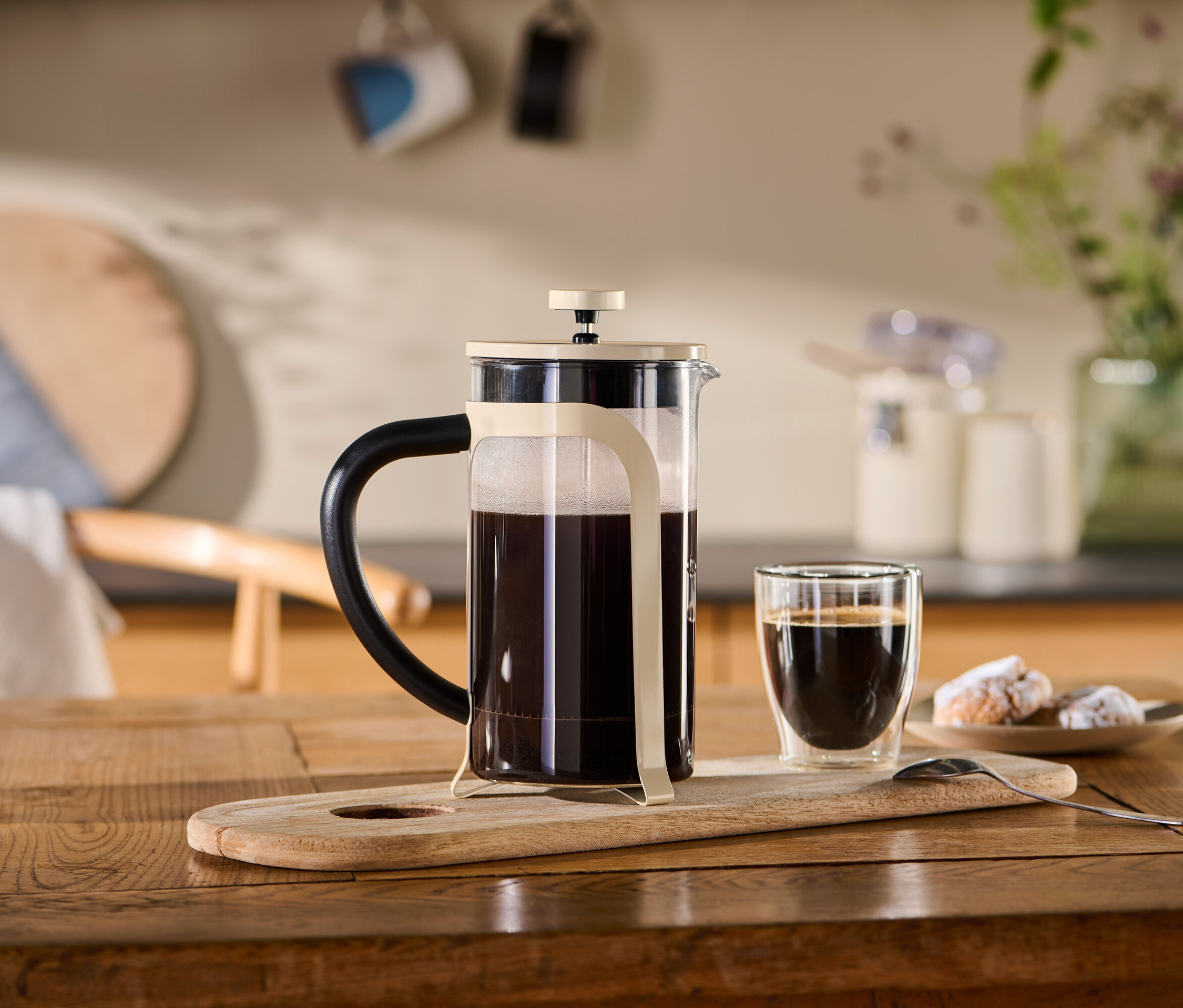 Béžová kanvica french press (800 ml, 6 šálok) stojí na drevenom podnose vedľa šálky kávy.