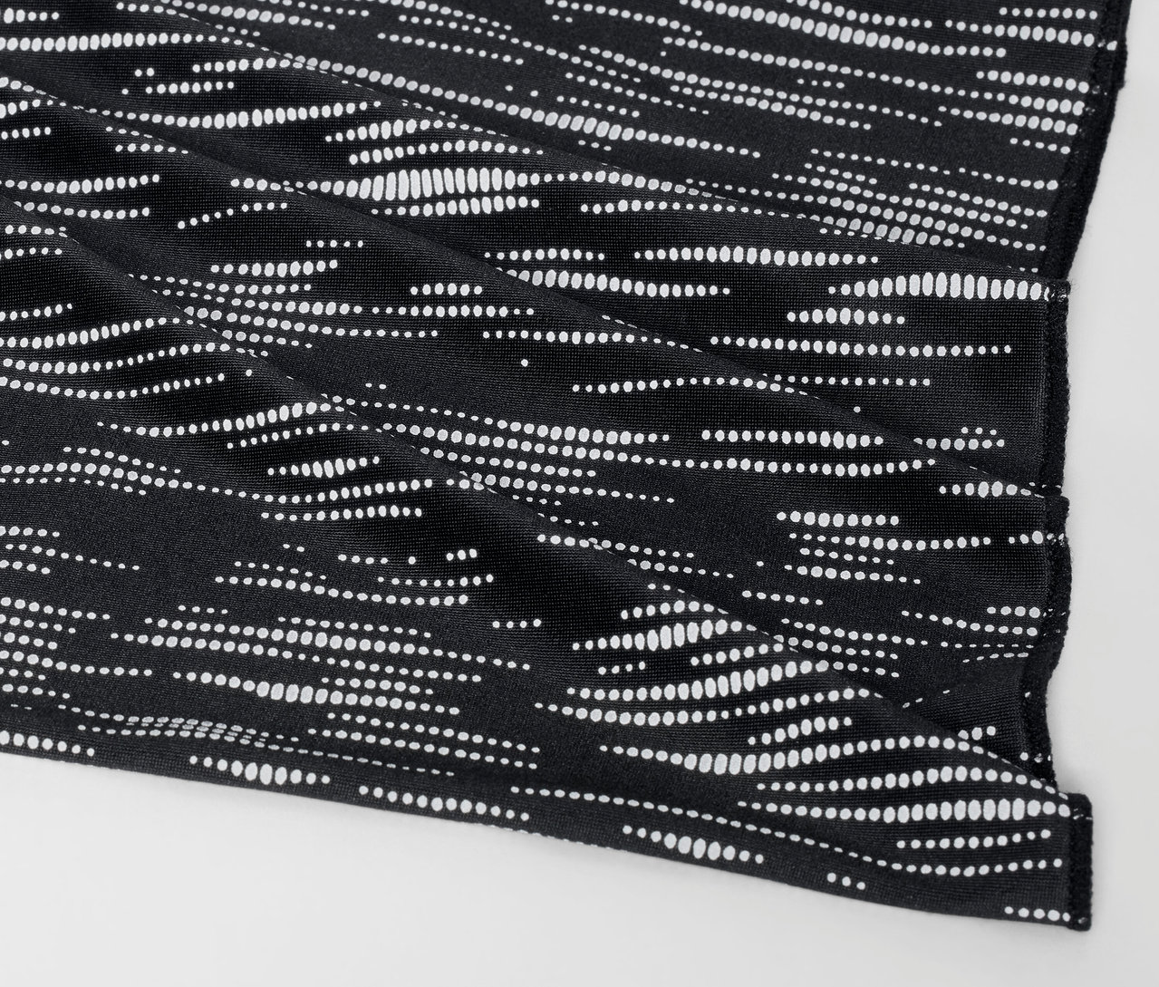 Detail čierneho látkového obalu s bielym bodkovaným vzorom.