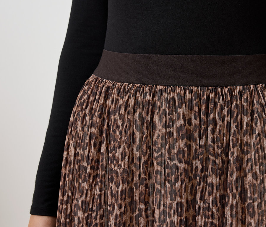 Detail dámskej sukne s hnedou leopardou potlačou a čiernym topom s dlhým rukávom.