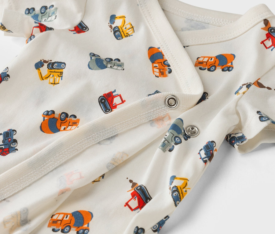 Detailný záber na biele detské body s potlačou stavebných áut.