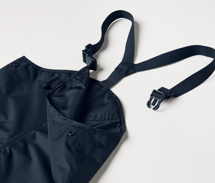 Modrá zástera s nastaviteľnými popruhmi a našitým vreckom na bielom pozadí.