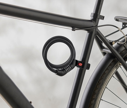 Detail čierneho rámu bicykla so špirálovým číselným zámkom pripevneným k rámu.