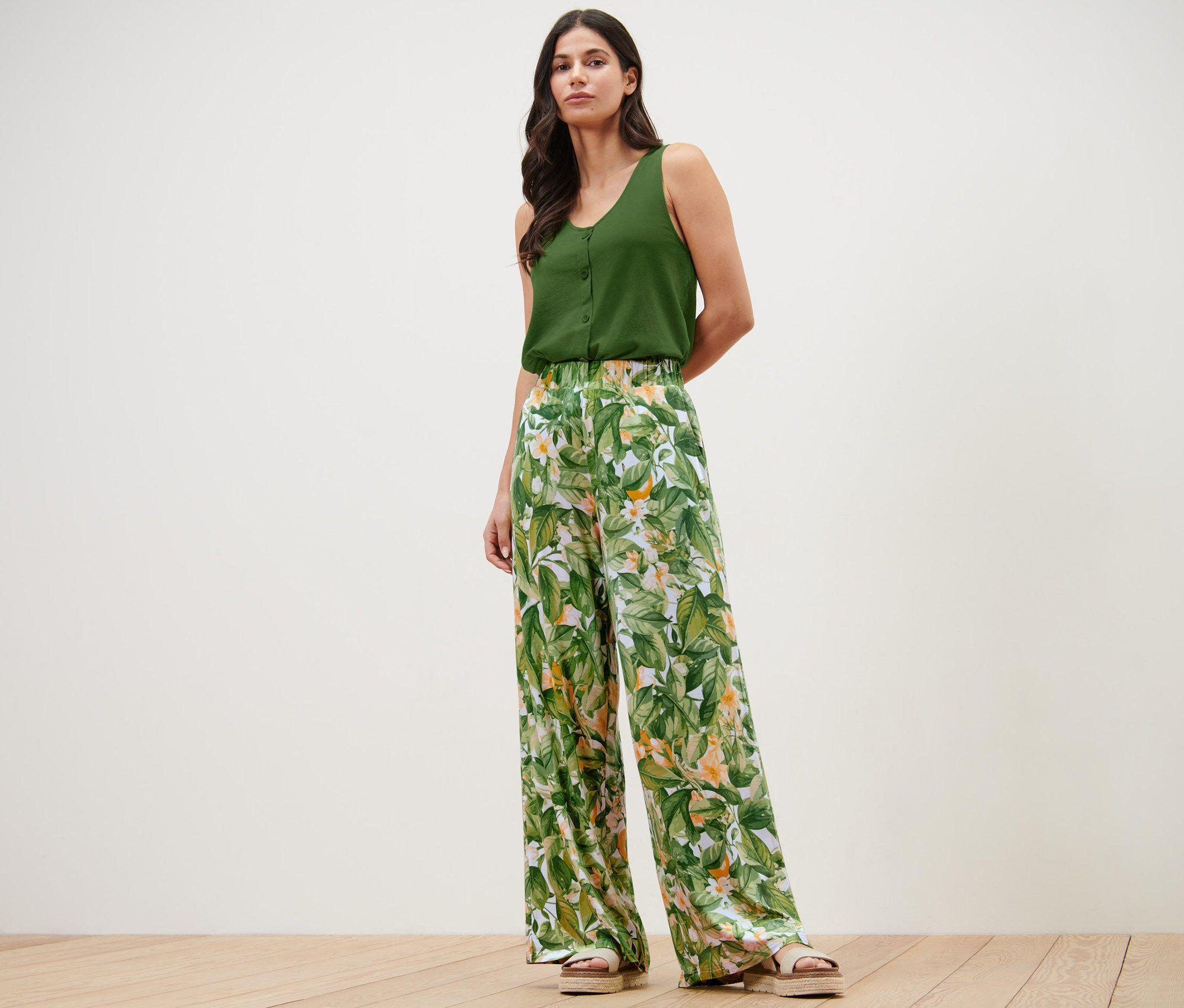 Žena pózuje v zelenom tope a nohaviciach v štýle palazzo s potlačou.