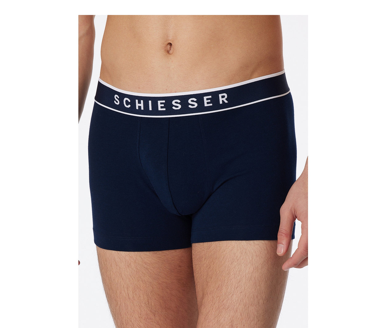 Muž má na sebe tmavomodré boxerky SCHIESSER s bielym pásom.