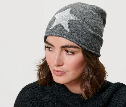 Žena má na sebe šedú čiapku typu beanie z jemného úpletu s trblietavými hviezdami.
