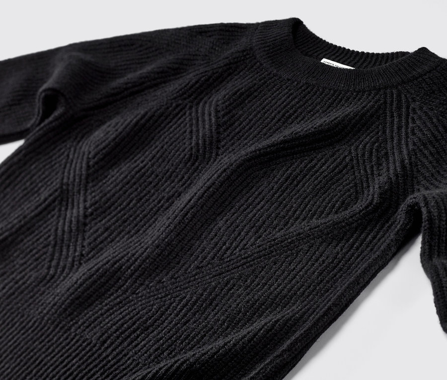 Detail čierneho pleteného pulóvra.