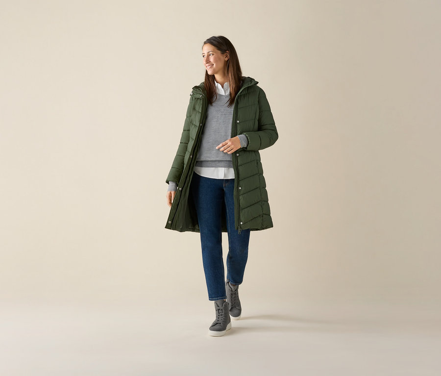 Žena má na sebe sivý pulóver z jemného úpletu s merino vlnou, zelenú bundu a džínsy.
