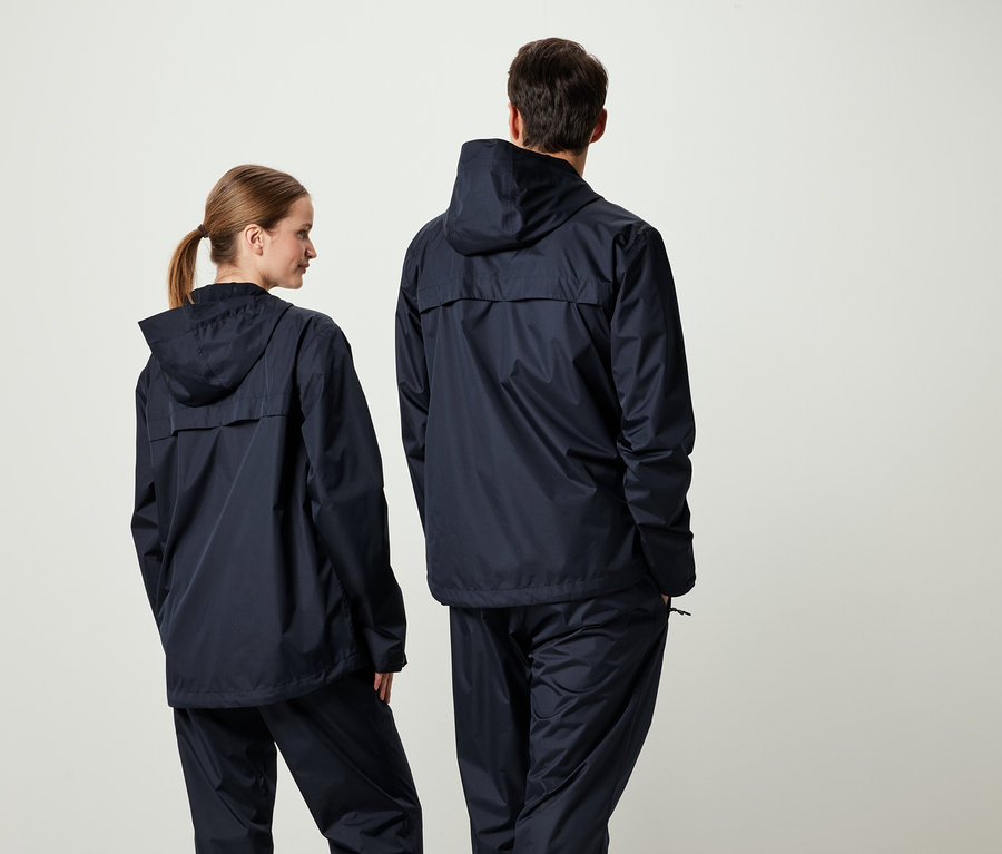 Dvaja ľudia chrbtom k fotoaparátu v zodpovedajúcich tmavomodrých bundách s kapucňou a nohaviciach.