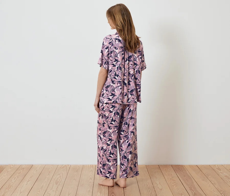 Žena stojí chrbtom k fotoaparátu a má na sebe pyžamo s kvetinovým vzorom.