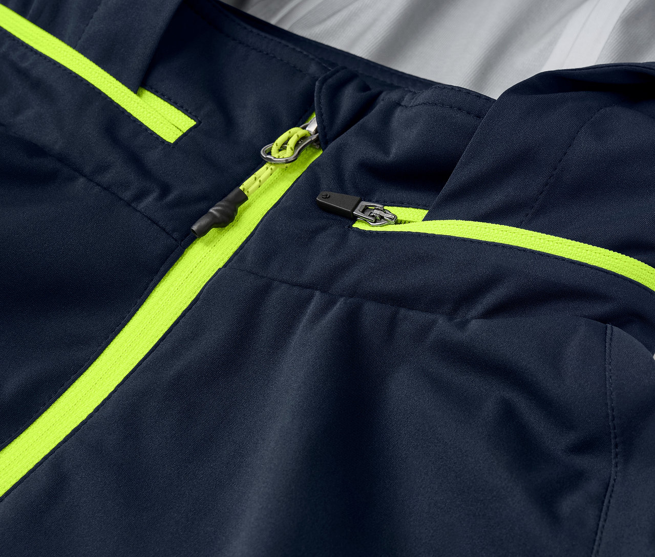 Detailný záber na cyklistickú bundu do dažďa s neónovo žltými detailmi zipsu a lemovaním.