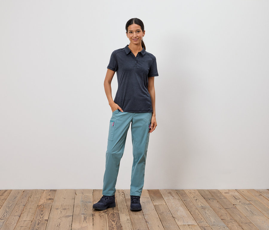 Žena stojí s rukou vo vrecku pred bielou stenou.