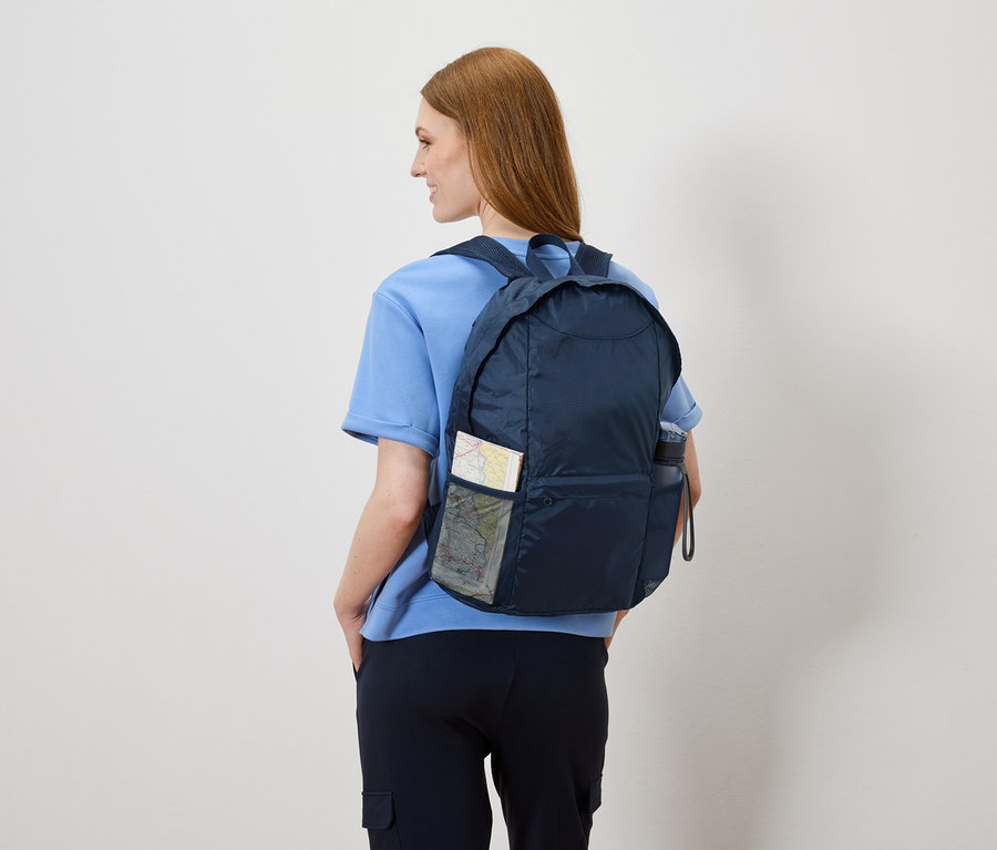 Žena zozadu s tmavomodrým ruksakom, v ktorom je mapa a fľaša s vodou.