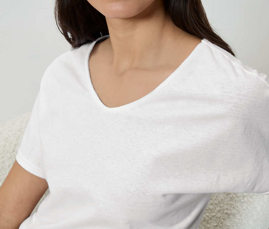 Žena má na sebe biele tričko s výstrihom do V.