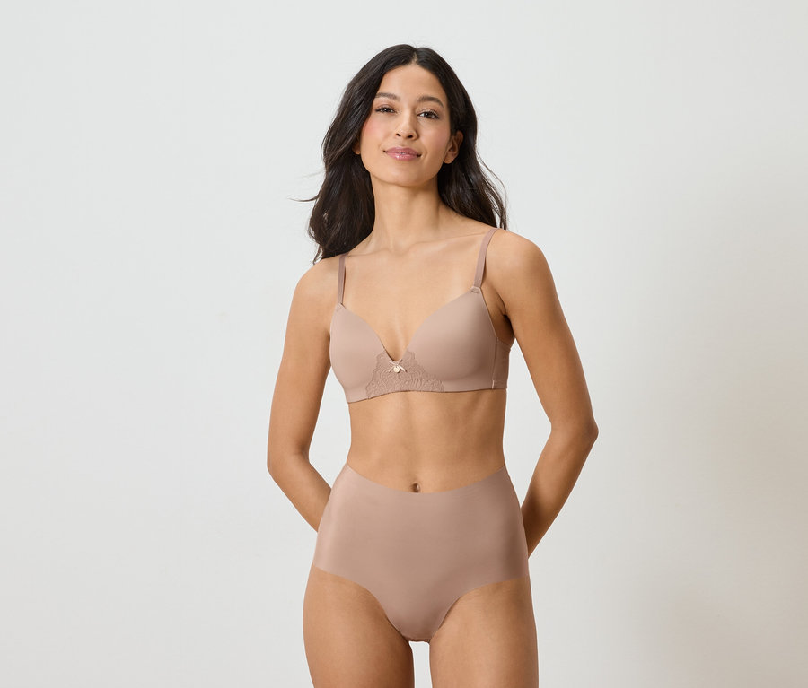 Žena má na sebe telovú podprsenku a nohavičky na bielom pozadí.