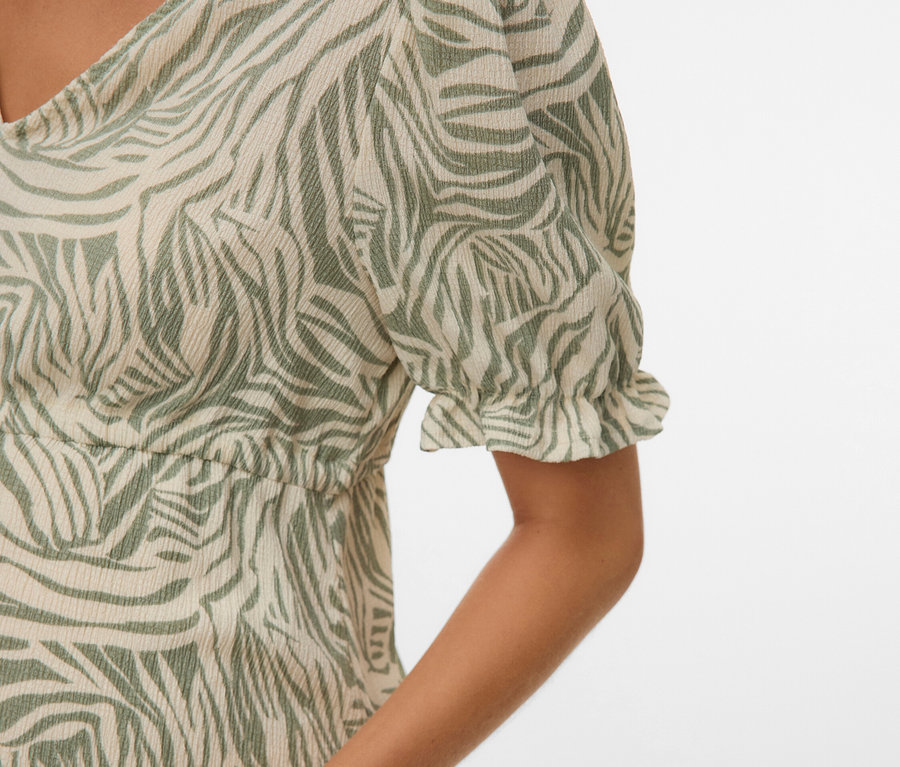 Detailný záber ženy v šatách so zeleným zebrovým vzorom.