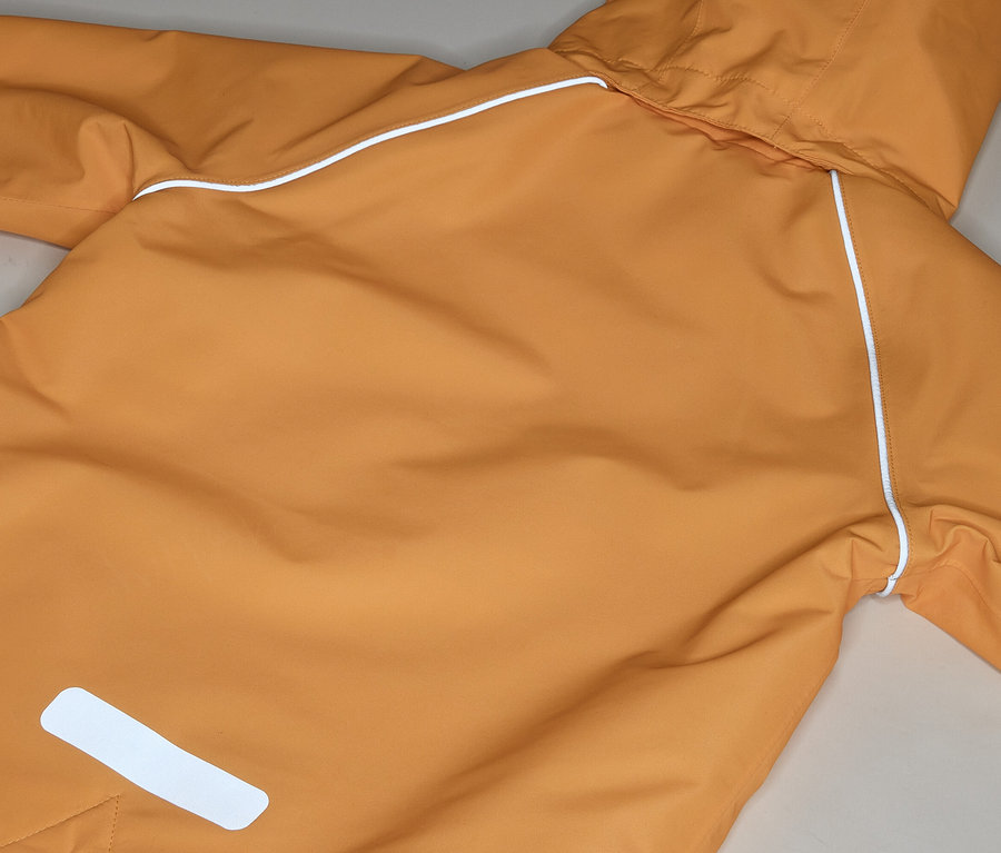 Detail oranžovej bundy do dažďa s kapucňou a bielymi odrazkami.