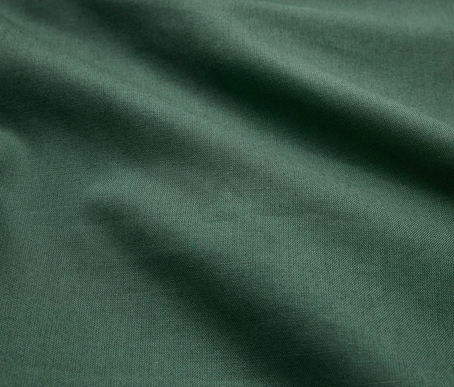 Zelená látka s záhybmi a jemnou textúrou.