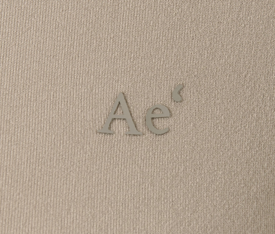 Detail hnedosivého funkčného trička s dlhým rukávom a logom "Ae".