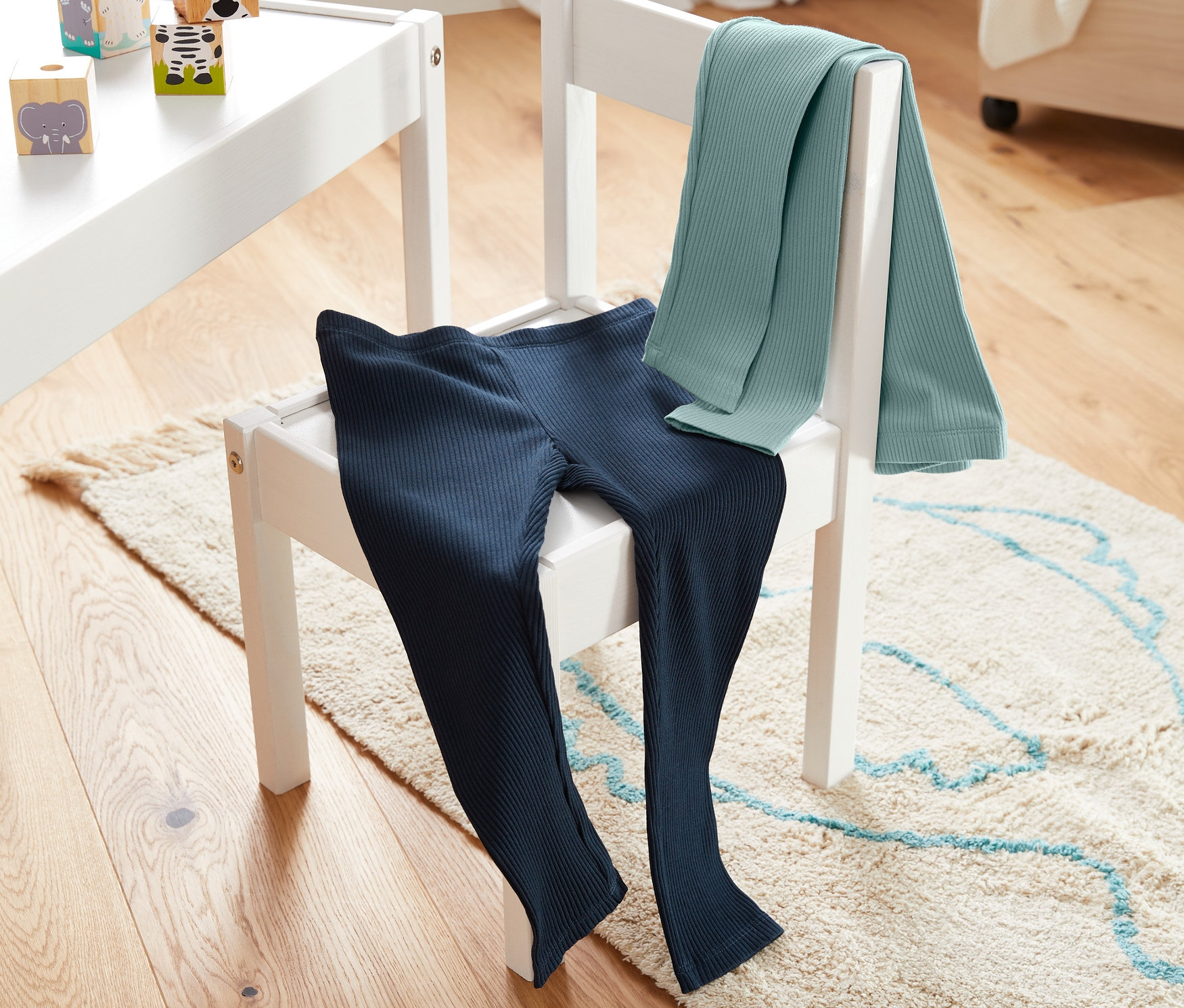 Na bielej stoličke ležia dvoje rebrované legínsy.