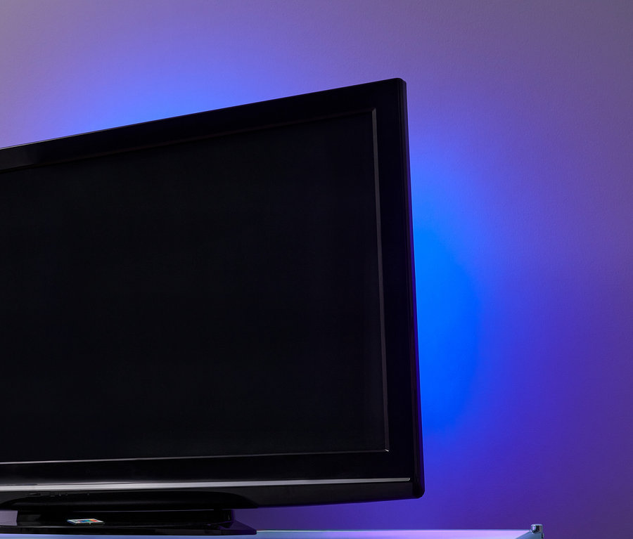 Čierny televízor s LED podsvietením TV na stene s fialovo-modrým svetlom.