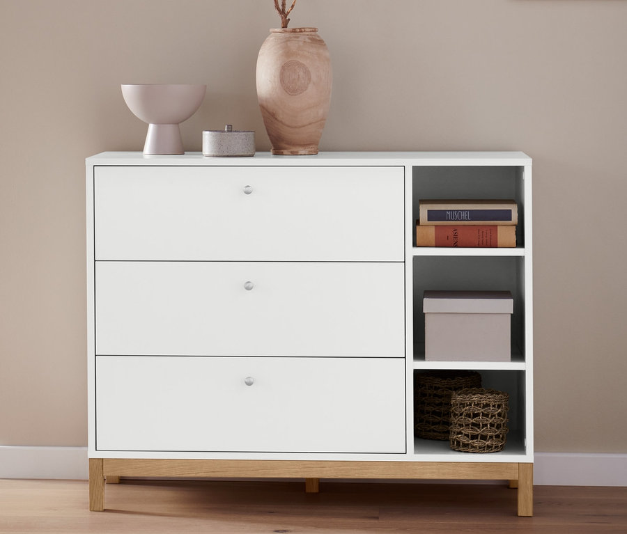 Čiastočný pohľad na spálňu s americkou posteľou Scapa svetlosivej farby, cca 160 x 200 cm a bielou komodou s úložnými košíkmi, 2 ks.