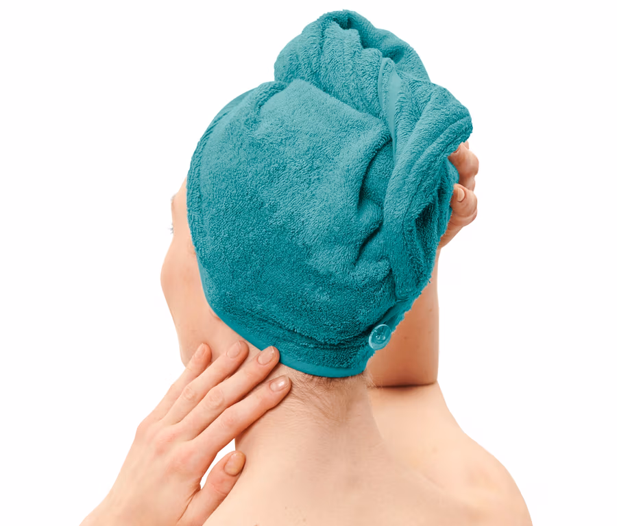 Žena si upravuje na hlave akvamarínový uterákový turban.