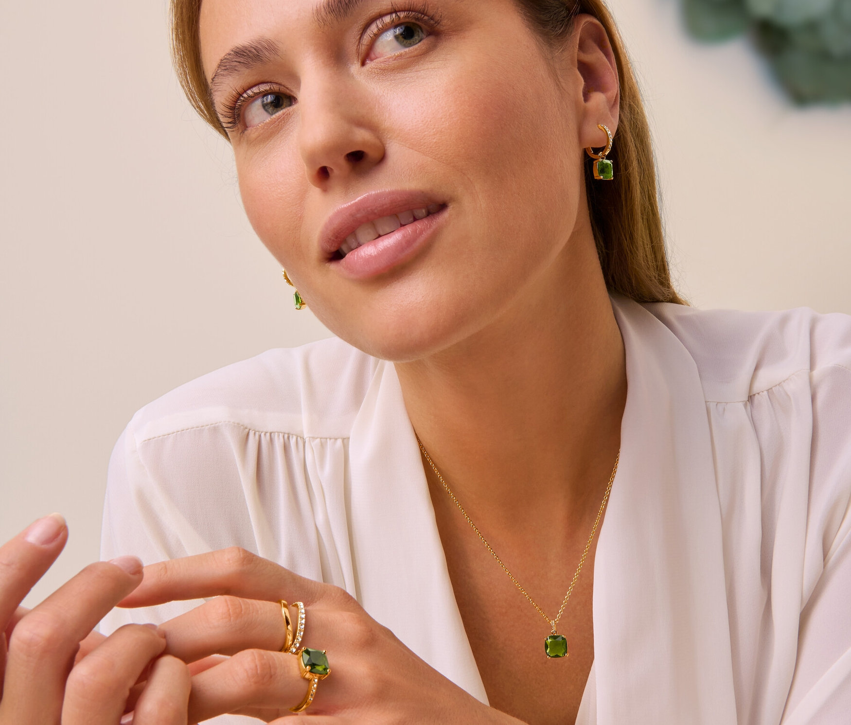 Žena má na sebe retiazku Forest so zeleným skleným krištáľom, kruhové náušnice Forest so zeleným skleným krištáľom, prsteň Forest so zeleným skleným krištáľom a prsteň dvojitá vlna s krištáľmi.