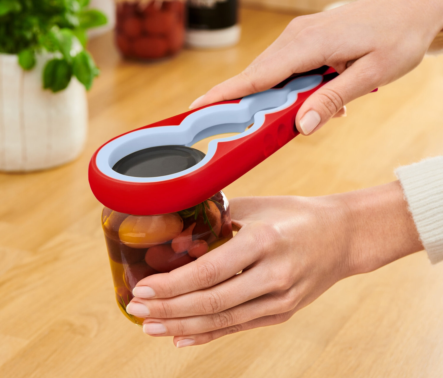 Žena otvára pohár s červeným otváračom na poháre a fľaše.