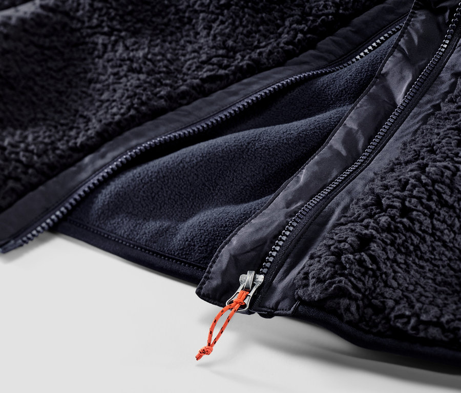 Detailný záber na zips plyšovej vesty.