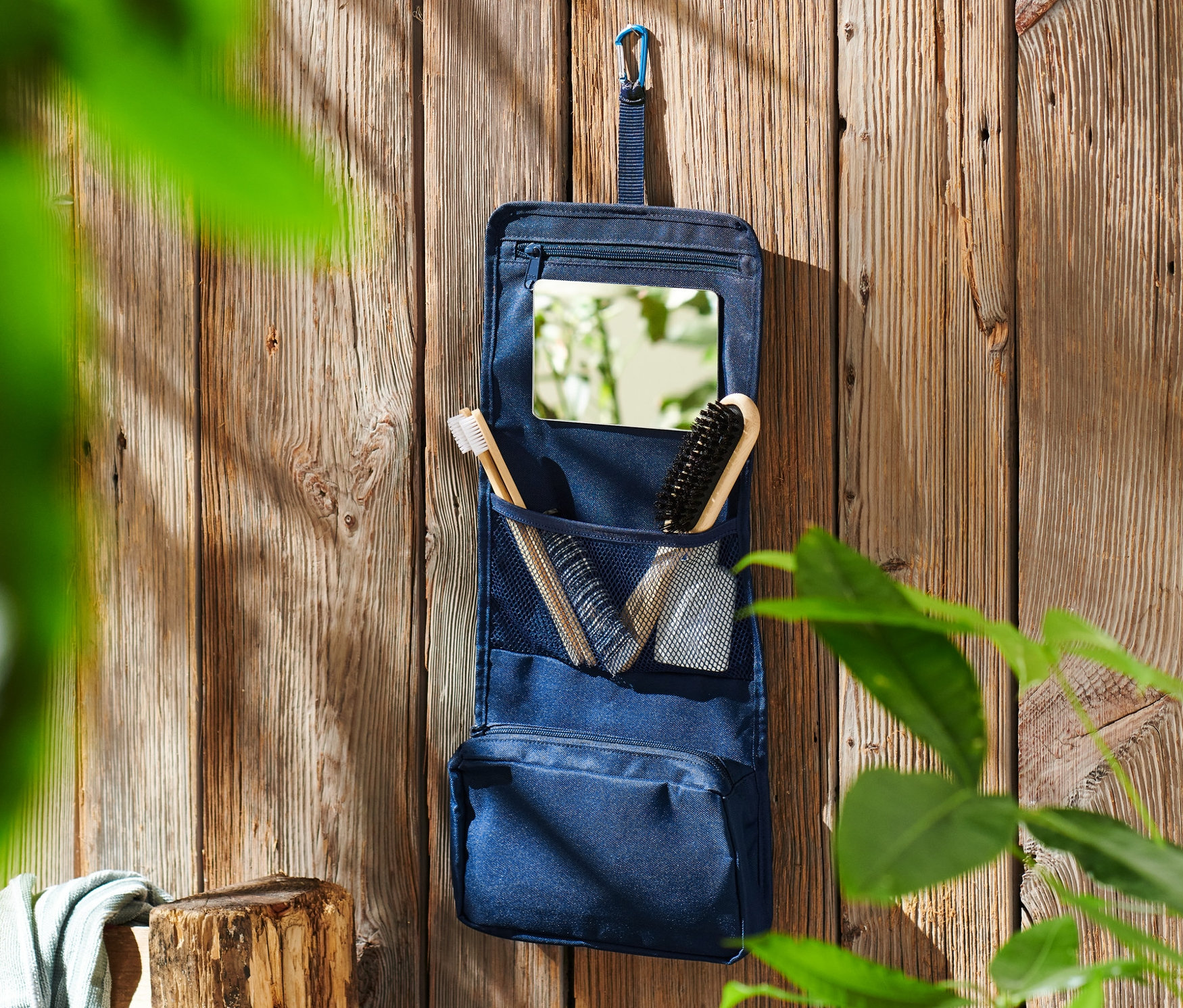Modrá toaletná taštička visí na drevenej stene.